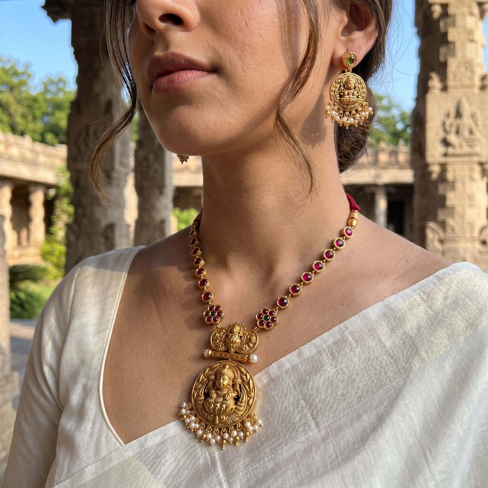 Model outdoors wearing reversible temple jewellery set below the collarbone, with sharp focus on stones, gold finish, and micro-details.